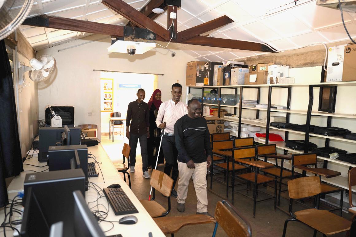 A photo of Kyebagadha Binsali, the Head of KyU Hi-Techn Center, guides UDHAN team members to the visual training center in the Faculty of Special Needs, where they will begin their training on braille production and digital inclusion.